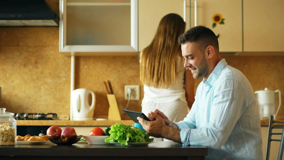 Для пары: как вернуть близость вдвоём, когда желание разное. Man using tablet in kitchen while woman stands behind him Фото: Vitaly Gariev, Unsplash