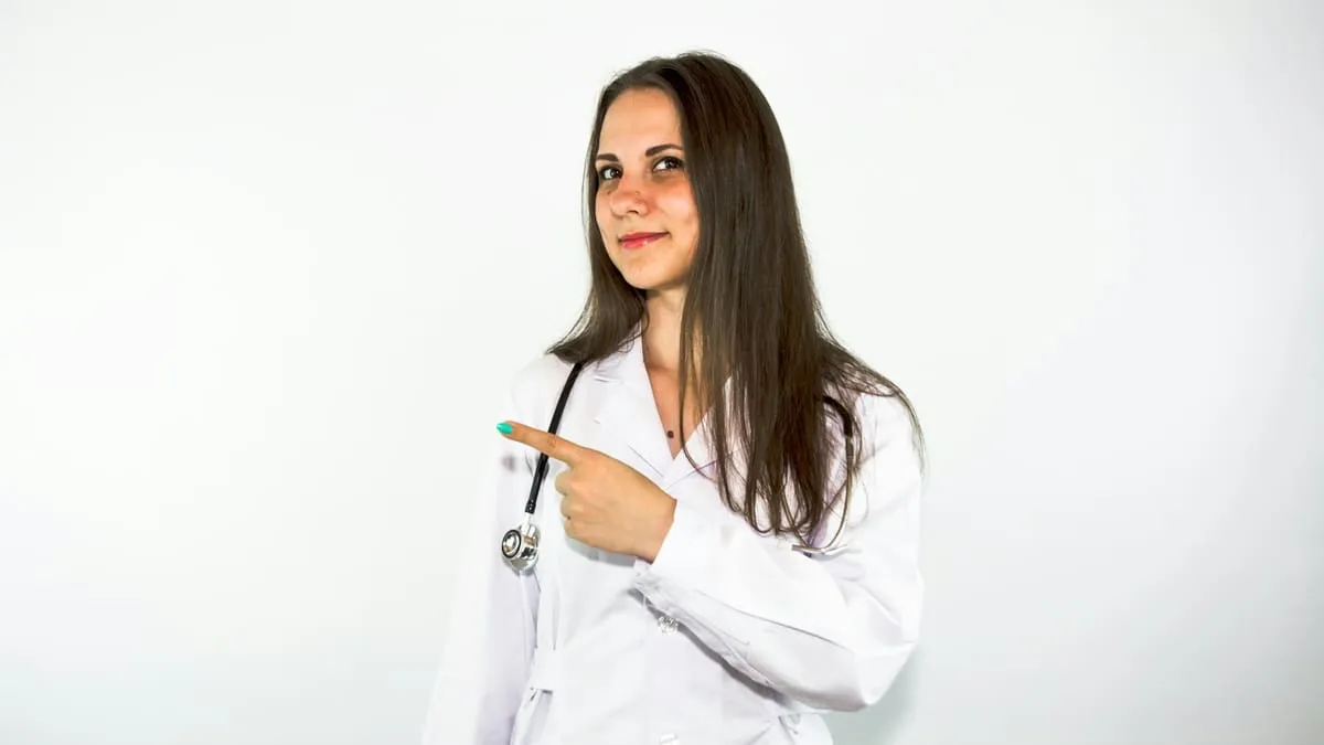 Молочница у женщин: причины, симптомы, что делать. a woman in a white lab coat pointing at something Фото: Bermix Studio, Unsplash