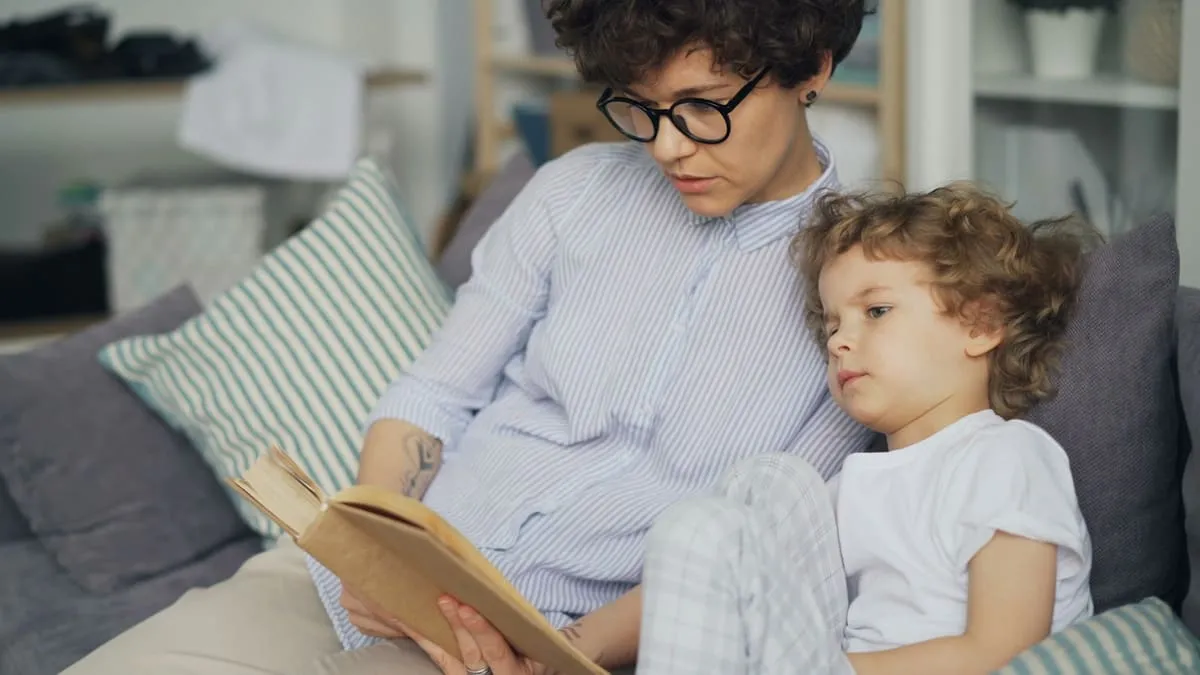 Половое воспитание детей: как говорить про «это» по возрастам. a woman sitting on a couch reading a book to a child Фото: Vitaly Gariev, Unsplash